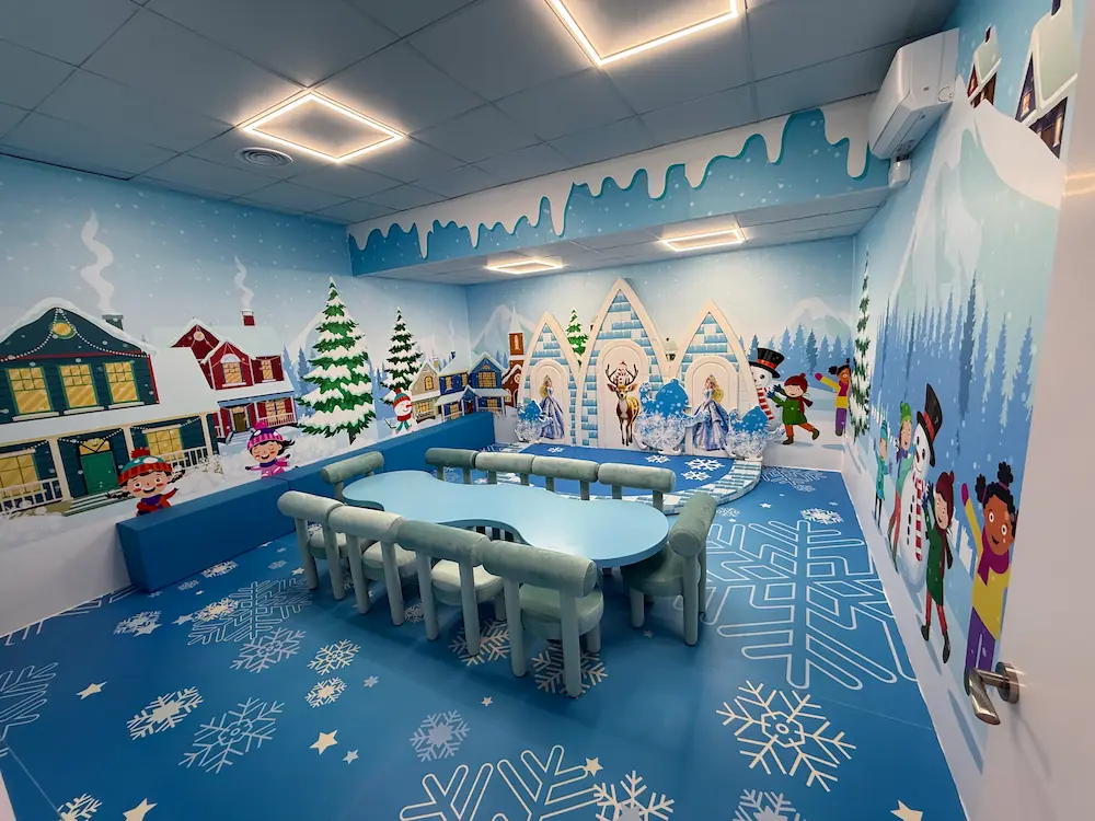 Sala infantil temática de invierno con nieve, casas y muñecos de nieve.